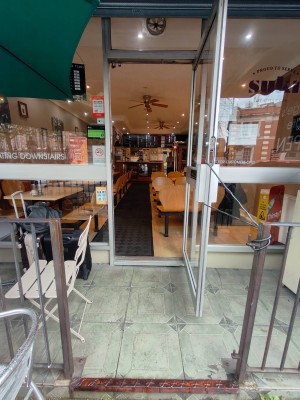 Facing entrance door. Silver framed door. Pull handle on left to open.
