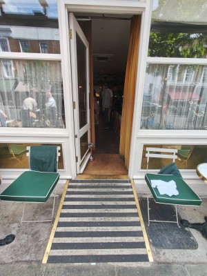 Facing entrance door. Built-in ramp ahead leads to white framed door. Push handle on right to open.