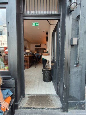 Facing entrance door. Grey framed door. Push handle in centre to open.
