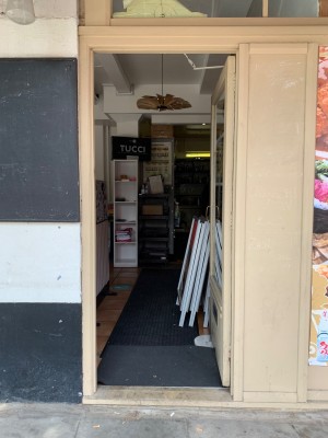 Glass door with beige wooden frame. Push from door handle on left of door to open.