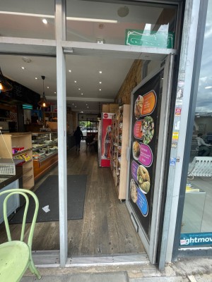 Single glass door with grey metal frame and large poster along door. Push grey handle on left to open.