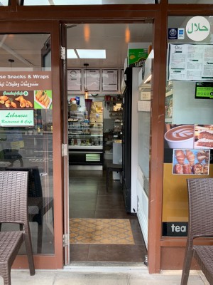 Glass door with brown metal frame. Push from gold metal handle on right of door to open.