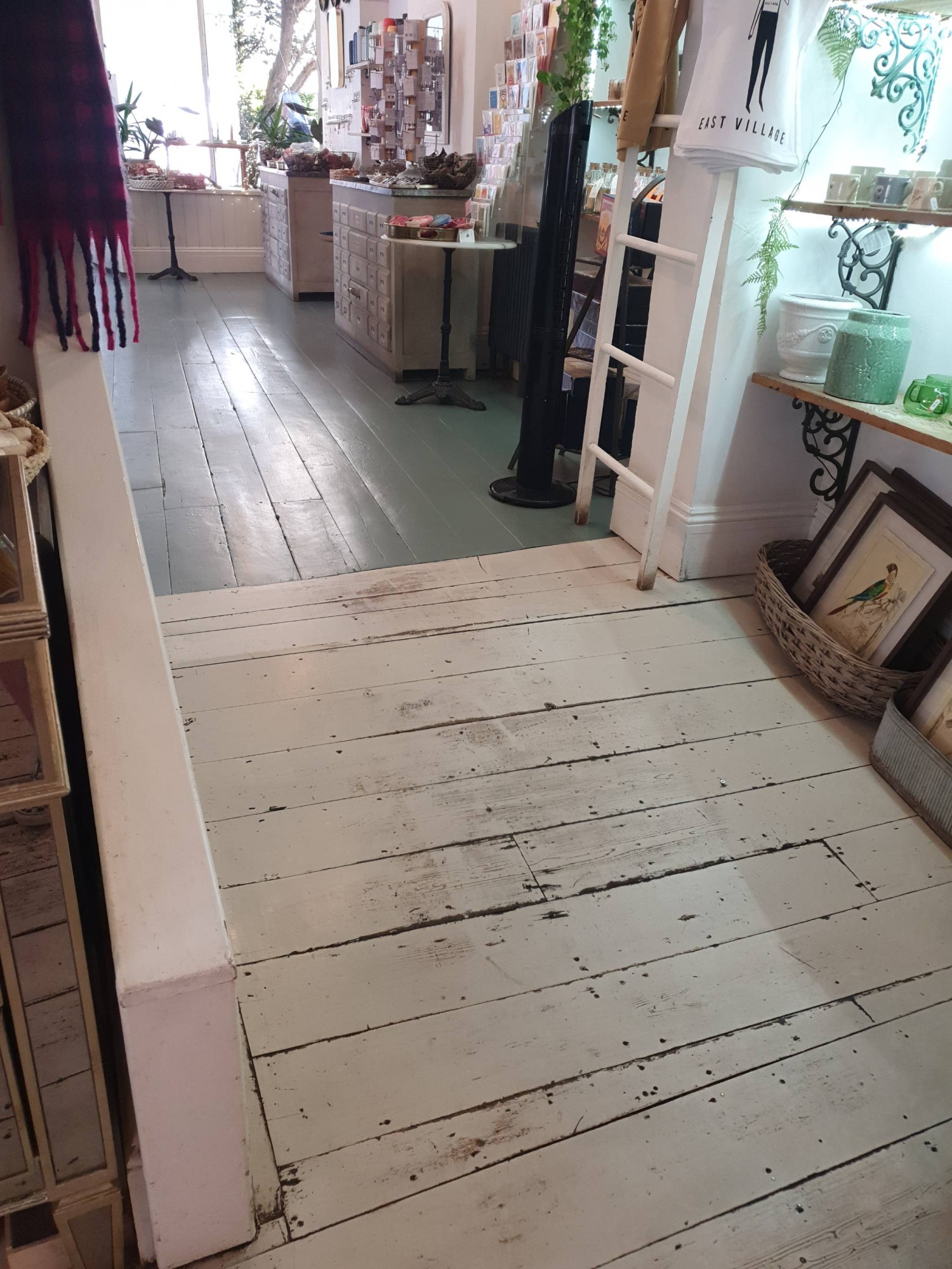 Shallow slope on wooden floor from cafe area to shop area through wide, open archway