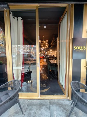 Facing entrance. Golden framed door. Push handle on left of right door to open.