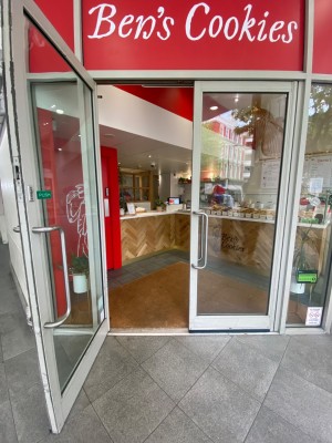 Double glass door, with grey doorframe. Silver handles at centre of door. Pull to open.