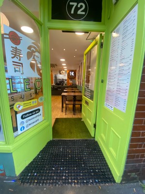 Glass door, with green wooden doorframe. Silver handle on left. Push to open.