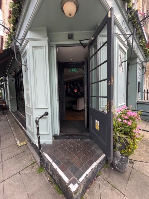Single black wooden door with glass panelling in light blue frame. Pull gold metal handle from left to open.