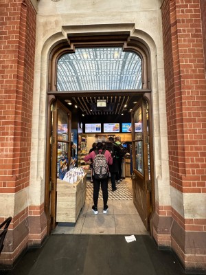 Double glass doors with wood doorframe. Push from centre to open. Display shelves to left inside door.