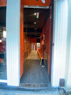 Glass door, with black doorframe. Handle on left. Push to open.
