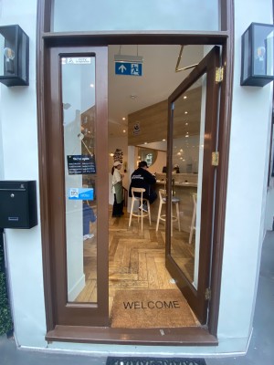 Glass door, with brown doorframe. Handle on left. Push to open.