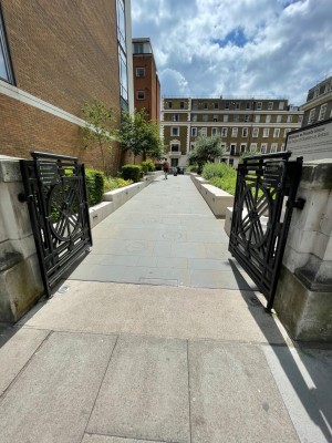 From the left of venue, looking left. Metallic double doors with handle in centre, push to open. Ramp pathway straight ahead.