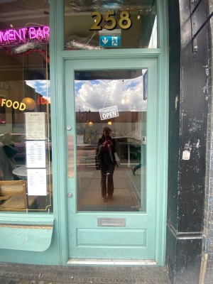 Glass door, with light blue doorframe. Push on left to open.
