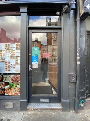 Glass door, with black doorframe. Silver handle on left. Push to open.