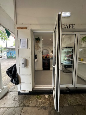 Glass sliding folding door with white doorframe. White handle to left of door. Pull to open. Doors can slide open to the right.