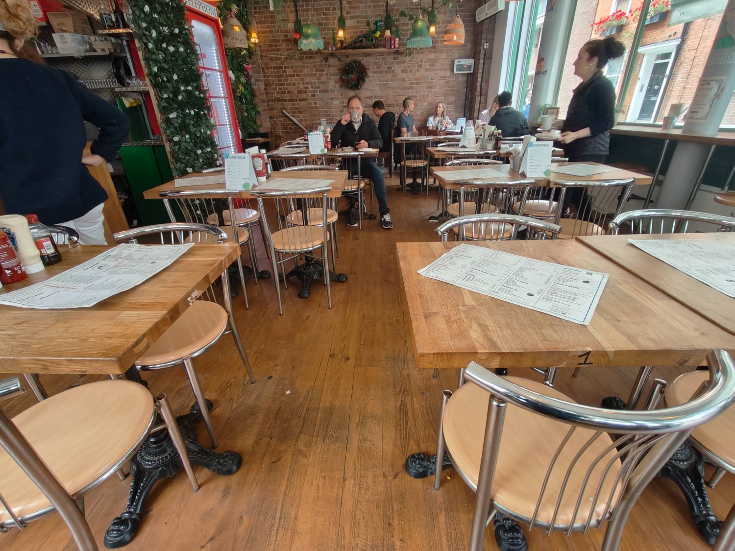 From mid path facing right. Counter on far left. Tables & chairs on left and right. Path in centre to table & chairs along back.  Stools at far right.