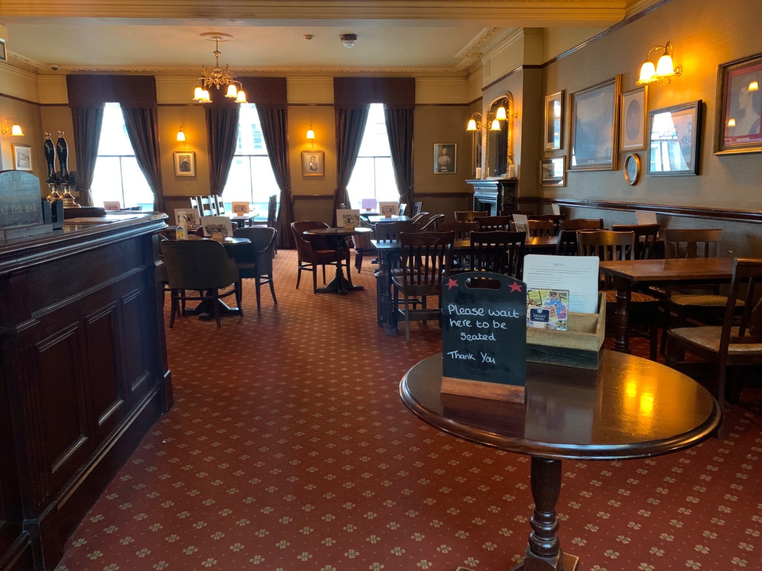 From doorway, looking straight. Table to immediate right. Counter along left wall. Path straight. Tables and chairs along right wall.