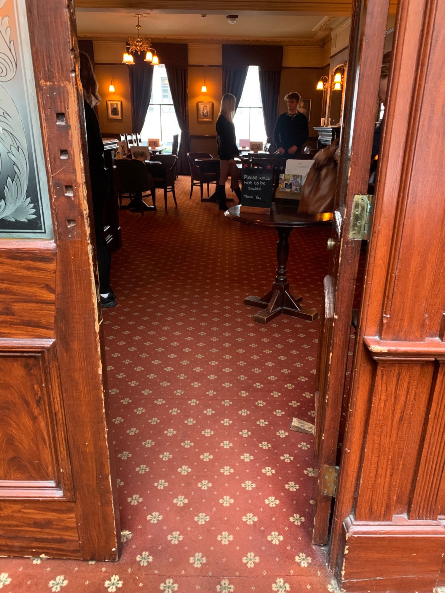 From top of staircase, looking right. Doorway to upstairs area ahead. Double glass doors with wooden frames. Push from center to open.