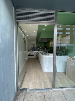 Glass door with grey dooframe. Silver vertical handle to right, push to open.