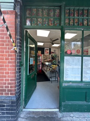 Single green wooden door with large glass panel. Push from right to open.