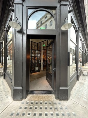 Single preceding black wooden door with large glass panel. Push from left to open.