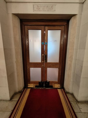 Facing entrance door. Wooden framed door. Push golden handles in centre to open.