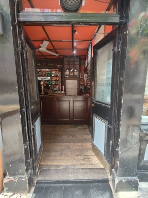 Facing entrance door. Black framed door. Push handles in centre to open.