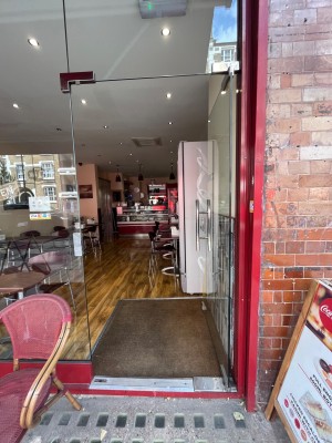 Single glass door in red metal frame. Push silver metal handle from left to open.