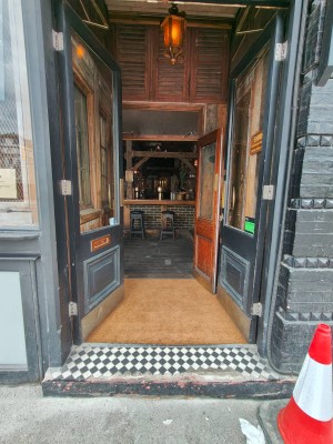 Facing entrance door. Grey framed door. Push golden metal handles in centre to open.