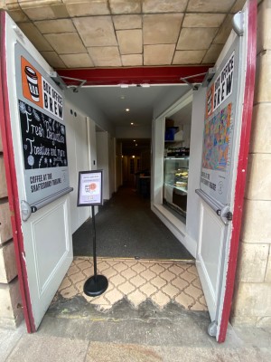 Double red wooden door. Pull to open. Sign on left, obstructing path.