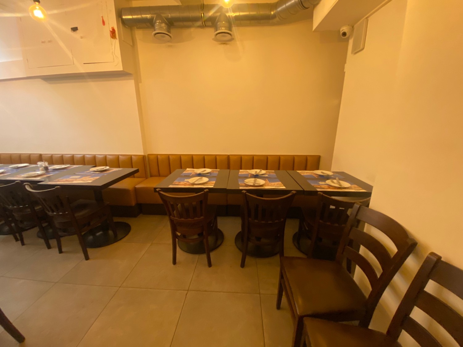 From door, facing right. Half booths, tables and chairs along back wall. Chairs on right.