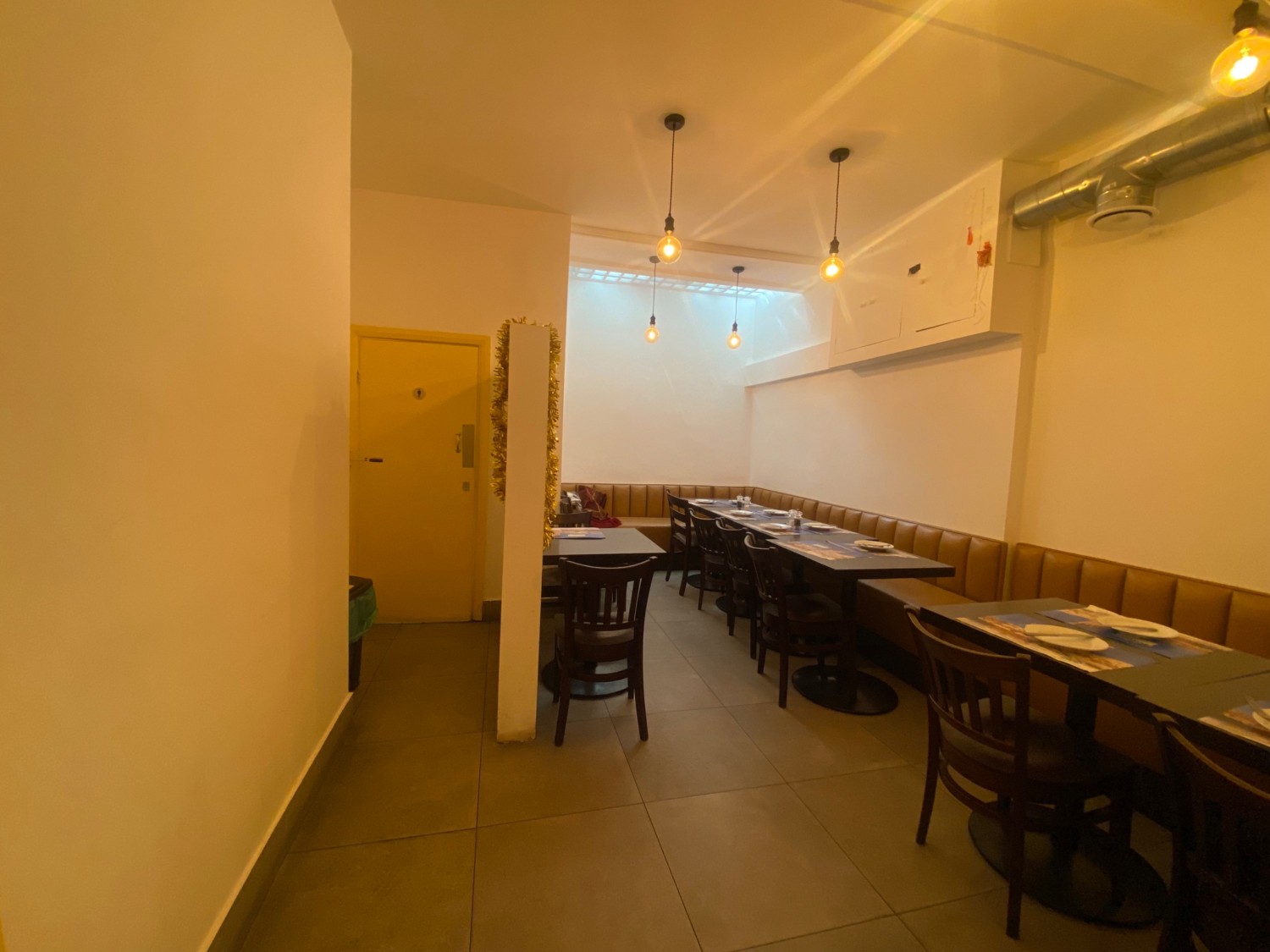 From door, facing straight. Half booth along right wall. Wall divider in front. Gents toilet to left of wall divider.