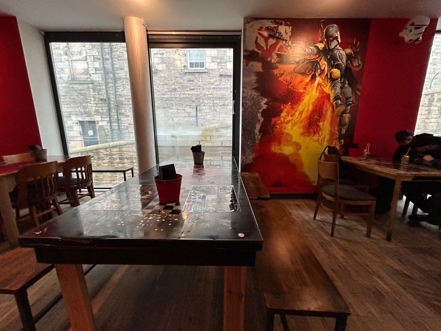 From start of counter, facing right. Tables and chairs on left and right. Table and benches ahead.