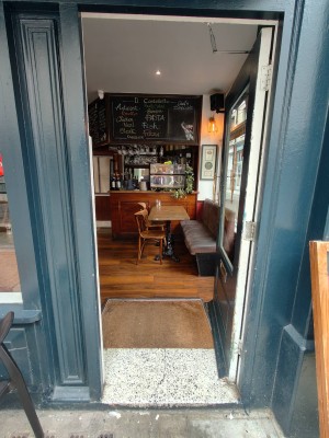 Facing green framed entrance door. Push golden metal handle on left of door to open.
