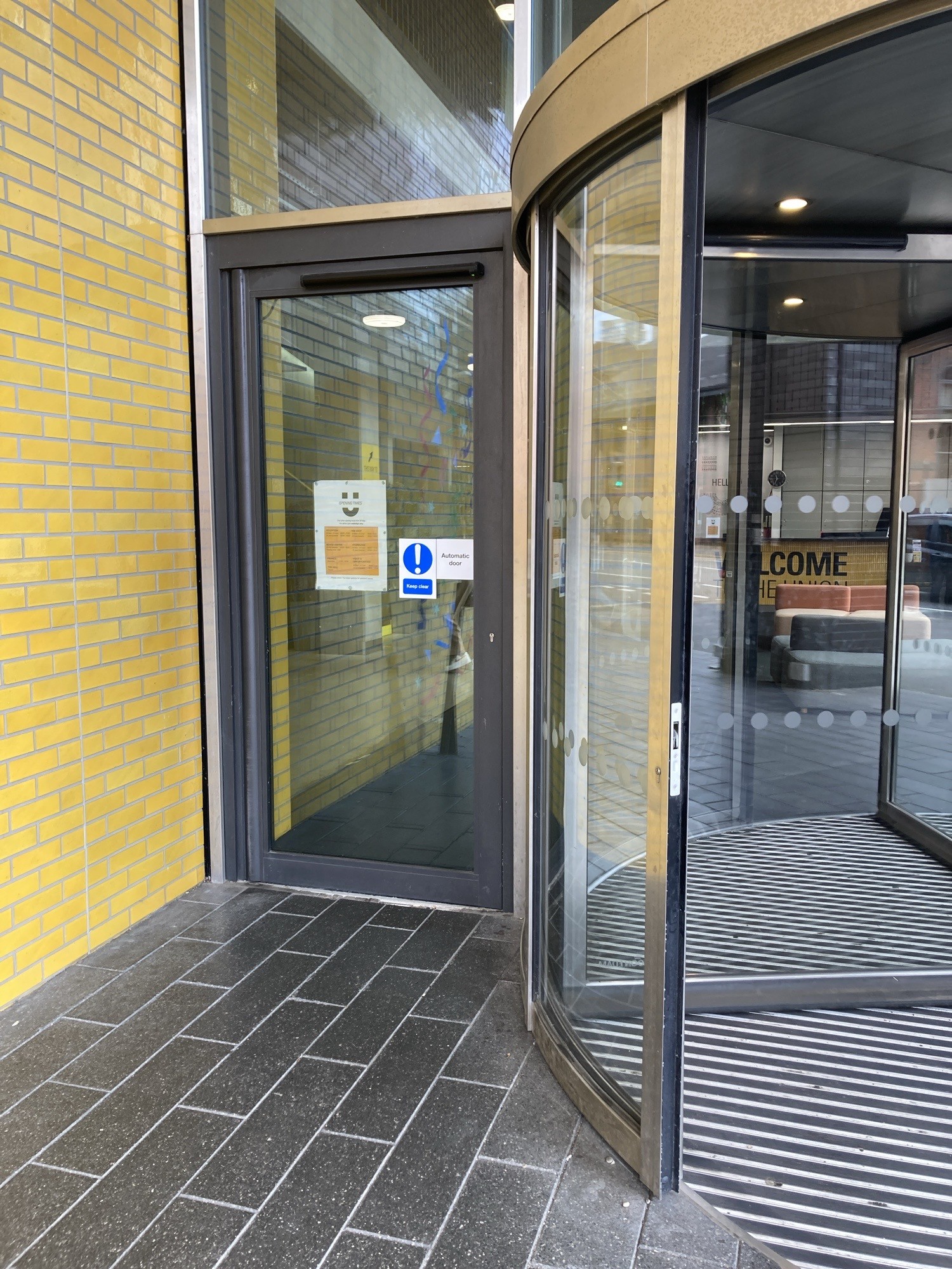 Single glass door to side of revolving door. Says automatic but ring for access.