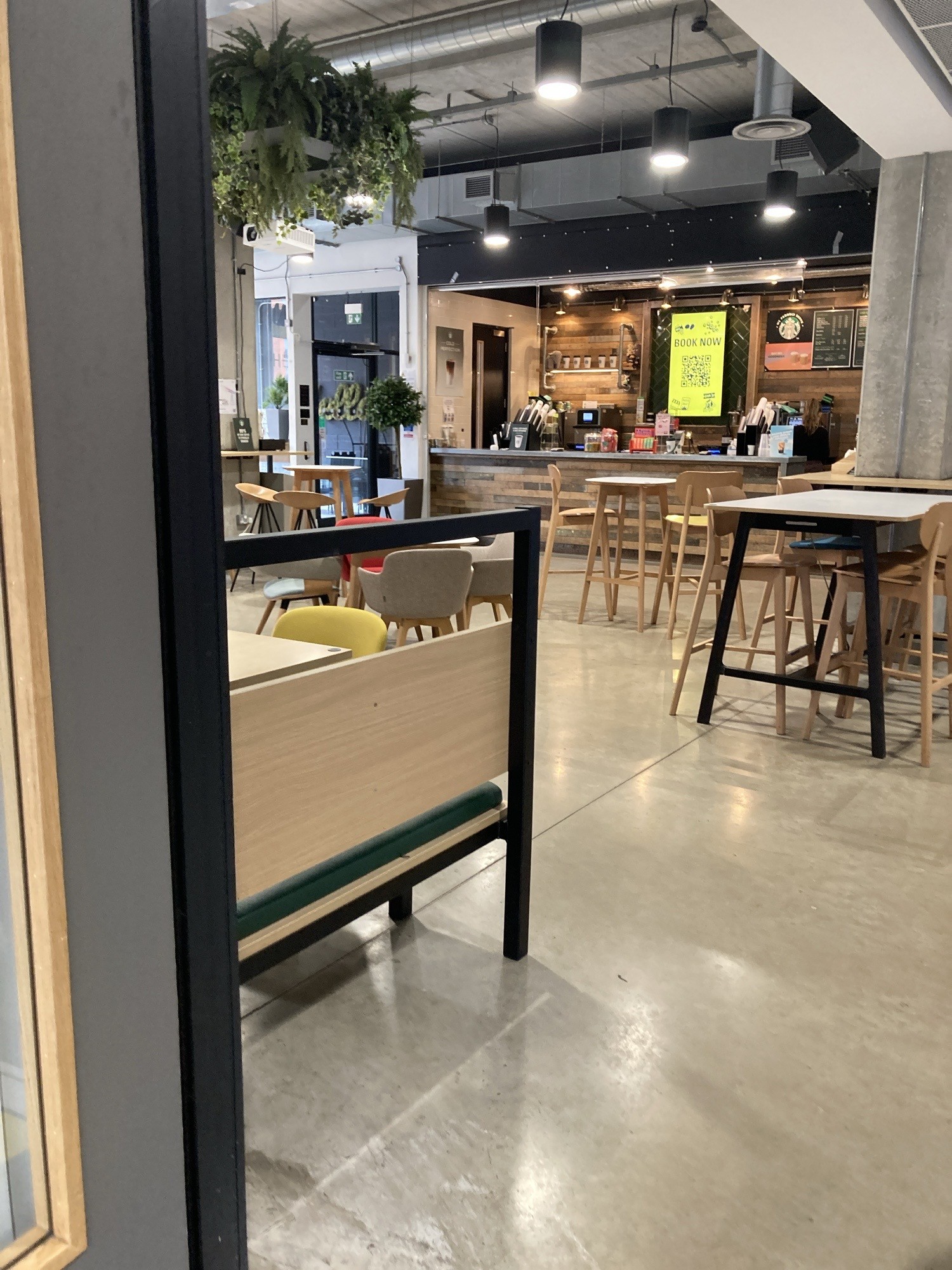 Internal entrance to Starbucks with mix of high and low tables and chairs