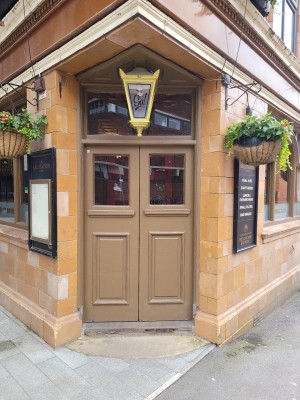 Wooden Double door entrance to pub. Another set of double doors as you enter. Small step.