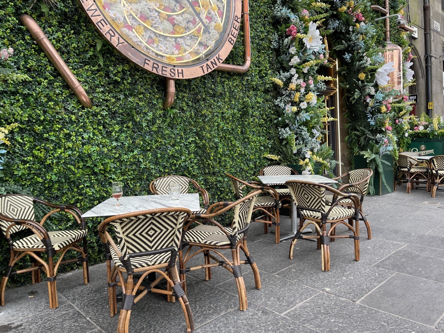 Three sets of table and four chairs to the right of the main entrance surrounded by plants