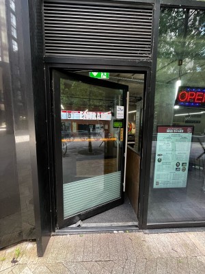 Glass door with black frame ahead. Push from silver handle on right to open.