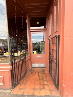 Black double gates, push from centre. Followed by pink and glass panelled door. Silver handle to left, push to open.