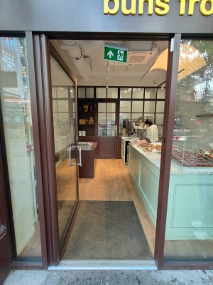 Facing brown framed entrance door. Push silver metal handle on right of door to open.