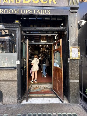 Wood and glass panelled door with vertical gold handles in centre. Pull to open.