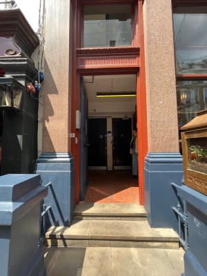 Single blue wooden door in orange frame. Push silver metal handle from right to open.