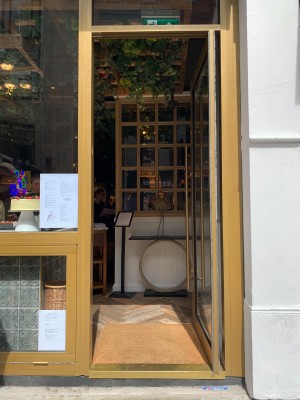 Single glass door with gold metal frame. Push from gold metal handle on left of door to open.