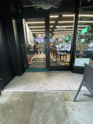 Glass door with black frame ahead. Pull from metal handle on right to open