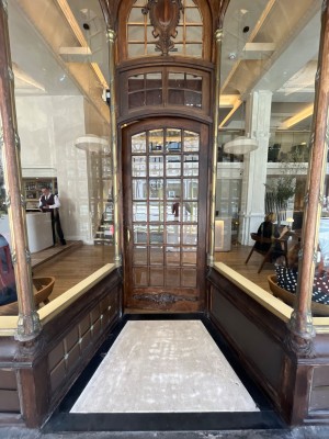 Wood and glass panelled door with gold handle to left of door. Push to open.