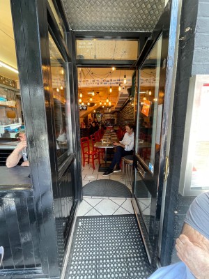 Single glass door with black wooden frame. Pull golden handle on left to open.