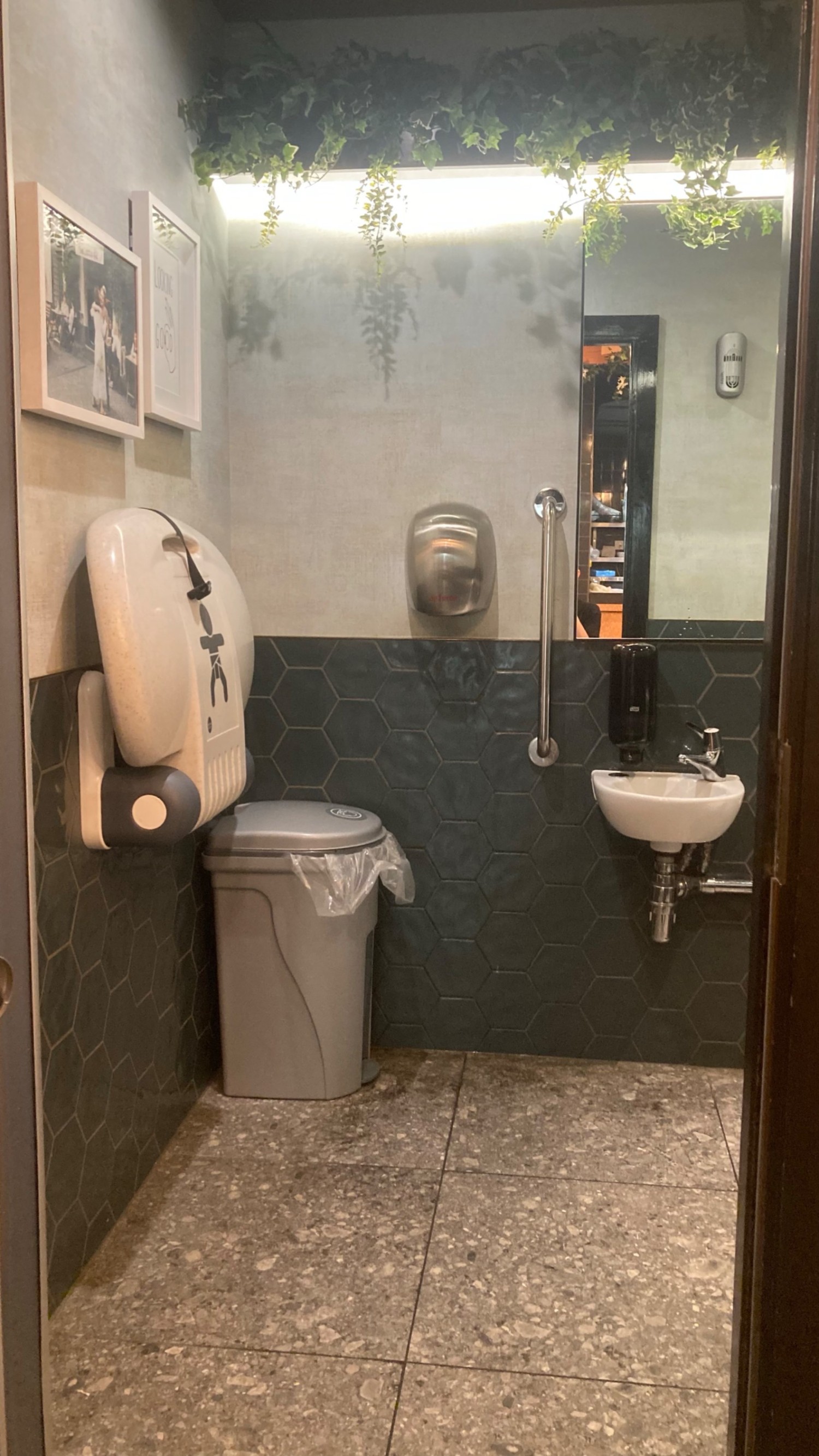 The entrance to the bathroom, with baby change table folded up, the sink and a mirror above.
