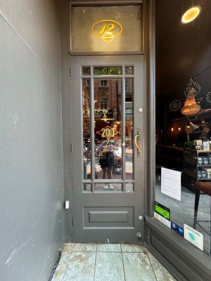 Single glass door in grey wooden frame. Pull gold metal handle from right.