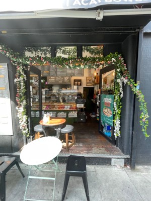Black glass double doors, handle in centre. Push to open. Seated at left obstructing part of entrance.