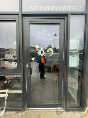 Glass door with grey frame. Pull metal handle on left to open.